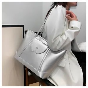 Detail of silver metallic tote bag with curved flap and rivet on a minimalist model setup