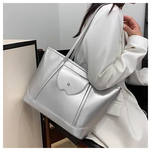 Detail of silver metallic tote bag with stylish wavy flap and round buckle on white suit