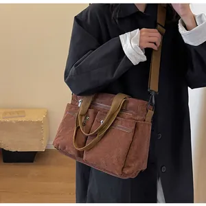 Brown corduroy tote bag with multiple zip pockets shown in a minimalist interior setting