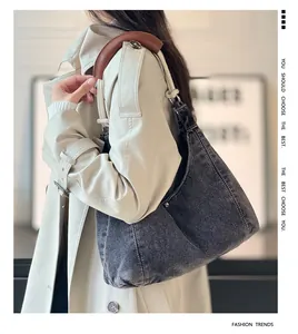Detail of washed denim tote bag with brown leather handles on shoulder for daily use