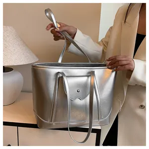 Detail of silver metallic tote bag featuring dual handles and front flap pocket