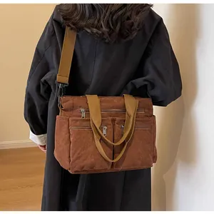 Detail of brown corduroy shoulder bag with three front zippers and wide fabric strap