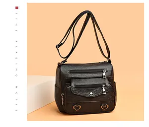 Detail of black faux leather bag with triple front zippers and heart metal accents