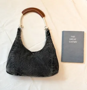 Detailed close-up of a denim hobo bag with rope handle and contrast stitching detail