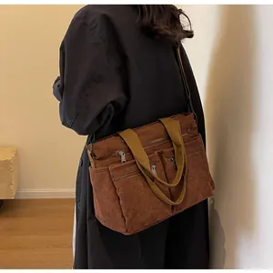 Detail of dark brown corduroy tote bag showing vertical texture and multiple front zipper pockets