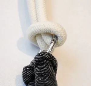Macro detail of thick beige woven strap and silver metal clasp on denim bag