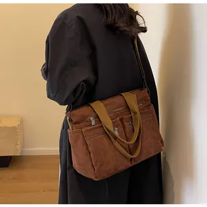 Detail of a brown corduroy shoulder bag with three functional zippered front pockets