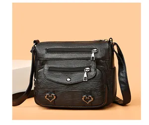 Close-up of black crossbody bag with litchi texture and multiple zipper pockets