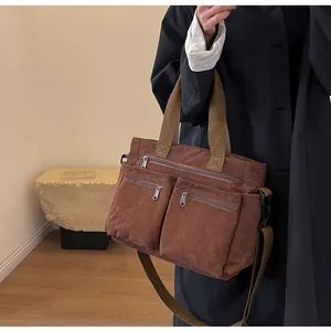 Detail view of a large brown corduroy tote bag with multiple zip pockets and adjustable strap