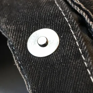 Detail of the magnetic attraction switch on the black denim crescent underarm bag