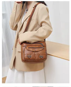 Brown vintage leather crossbody bag with multiple zip pockets and heart metal accents