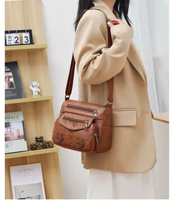 Close-up of brown vintage crossbody bag with heart rivets and multi-zipper pockets