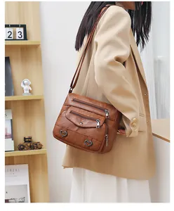 Detailed close-up of brown faux leather crossbody bag featuring heart-shaped metal accents
