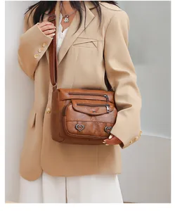 Detail of vintage brown multi-pocket crossbody bag with heart shaped metal ornaments