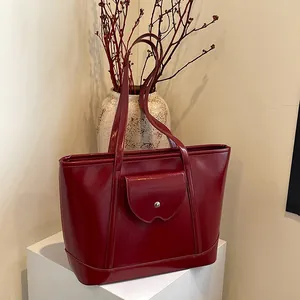Elegant deep red polished leather tote bag with silver buckle pocket on a white pedestal