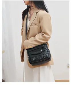 Close-up of black retro soft leather crossbody bag with heart buckles and multi-zippers