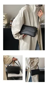 Détail d'un sac à bandoulière en cuir gaufré noir avec rabat et boucle dorée