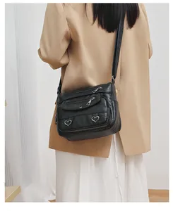 Detailed back view of a black retro crossbody bag with heart-shaped metal charms on a model