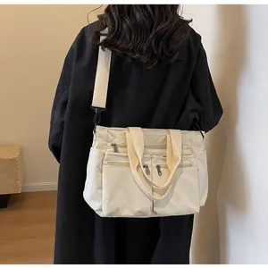 Detail of off-white corduroy tote bag featuring multiple front zippers and a wide shoulder strap