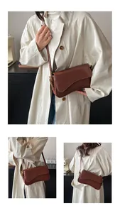 Gros plan détaillé montrant la texture gaufrée lézard et le rabat du sac bandoulière marron