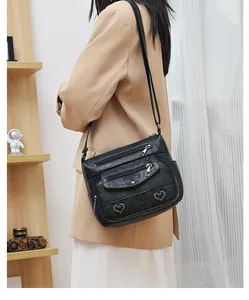 Detail of black vintage crossbody bag showing soft leather texture and metal heart buckles
