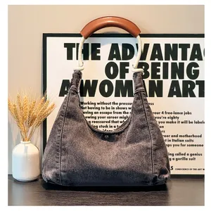 Detailed close-up of a washed denim hobo bag with a thick woven rope handle and snap button