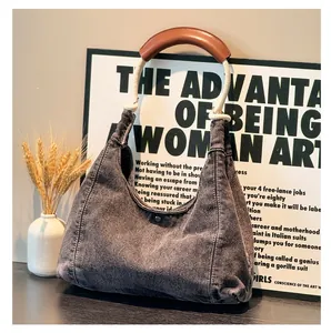 Detail of denim hobo bag with cotton rope handle and premium leather grip on dark table