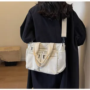 Detail of off-white corduroy crossbody bag showing multiple pockets and wide strap