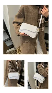 Vue détaillée de la texture cuir de crocodile blanc et du rabat asymétrique du sac à main