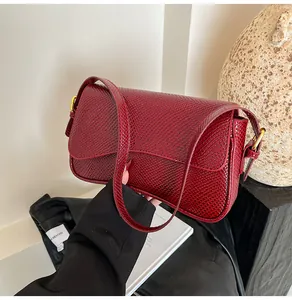 Détail du sac à bandoulière rouge foncé en cuir croco avec boucle en métal doré