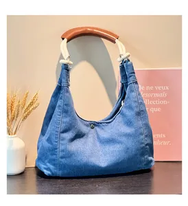 Detail of blue denim hobo bag with unique rope handle on a dark wooden surface