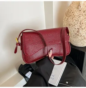 Détail du sac à bandoulière bordeaux avec texture animale et finitions dorées chic