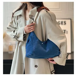 Close-up of denim shoulder bag with white cotton rope strap and brown leather pad