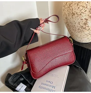 Détail de la texture cuir crocodile bordeaux et de la boucle en métal de la bandoulière