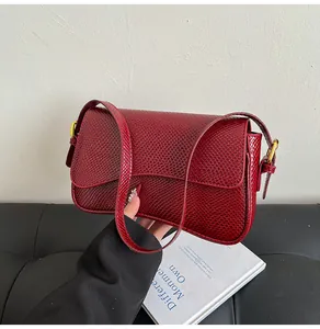 Détail du sac bandoulière bordeaux à texture animalière avec rabat et boucle dorée