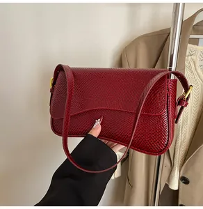 Détail d'un sac à main bordeaux à motif peau de serpent et boucle métallique dorée