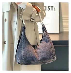 Detail of a black washed denim hobo bag featuring a white rope handle and brown leather pad