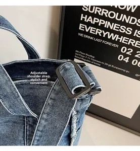 Close-up of adjustable shoulder strap with metal buckle on blue denim tote bag