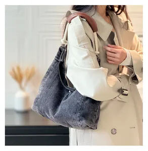 Detail of gray denim shoulder bag featuring thick white cotton rope straps and leather pad