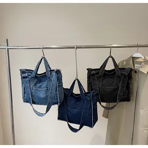 Detailed view of denim tote bags in light blue, dark blue and black with frayed edges
