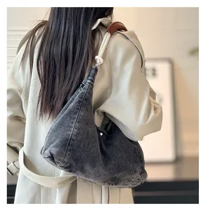 Detail of hobo bag featuring washed denim fabric and white braided rope shoulder strap