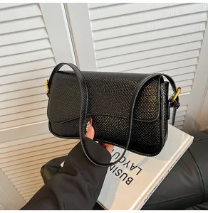 Gros plan d'un sac à bandoulière noir à motif serpent avec boucle en métal doré