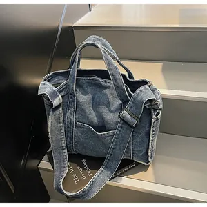 Detail of blue denim tote bag showing heavy washed edges and adjustable strap texture