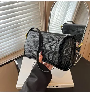 Détail du sac sous le bras noir en similicuir texturé avec boucle en métal doré