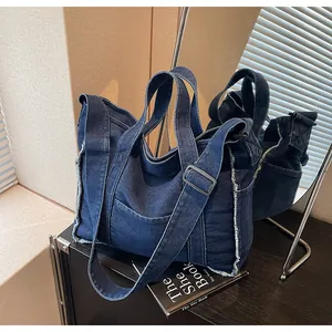 Detail of blue denim tote bag showing raw edges, large pockets and mirror reflection