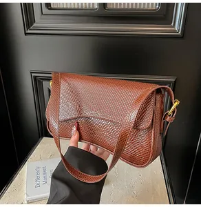Vue détaillée de la texture serpent marron et de la boucle dorée sur le sac à bandoulière