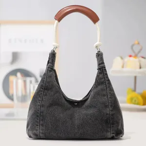 Deep blue denim hobo bag with white rope handle and brown leather grip in lifestyle setting
