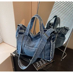Detailed macro of washed denim tote showing frayed edges, stitching, and side pocket