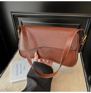 Détail du sac à rabat en cuir marron foncé effet serpent avec boucle dorée