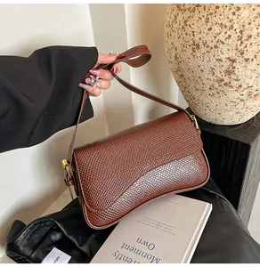 Détail d'un sac sous les aisselles en cuir crocodile marron avec boucle dorée élégante